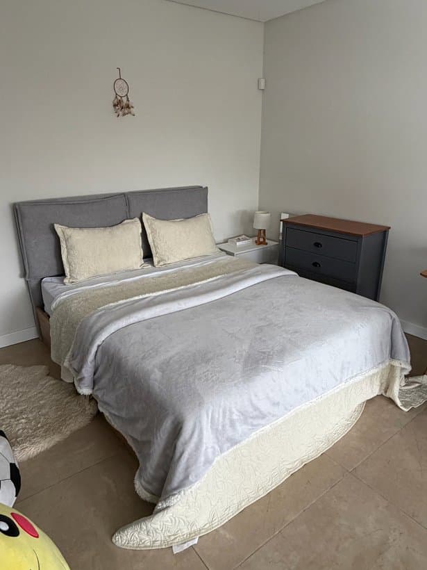 Cama de madera con cabecera tapizada y colchón